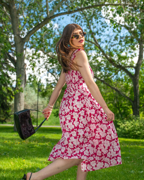 Woman in a red floral dress walking outdoors on a sunny day